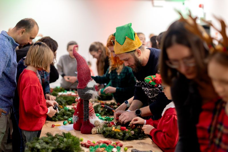 Pracownicy NTP z rodzinami podczas mikołajkowych warsztatów, wspólnie tworzący ozdoby choinkowe.