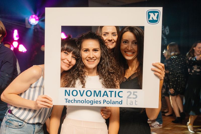 Uczestnicy imprezy Novomatic Technologies Poland pozujący z ramką do selfie podczas afterparty po uroczystej kolacji.