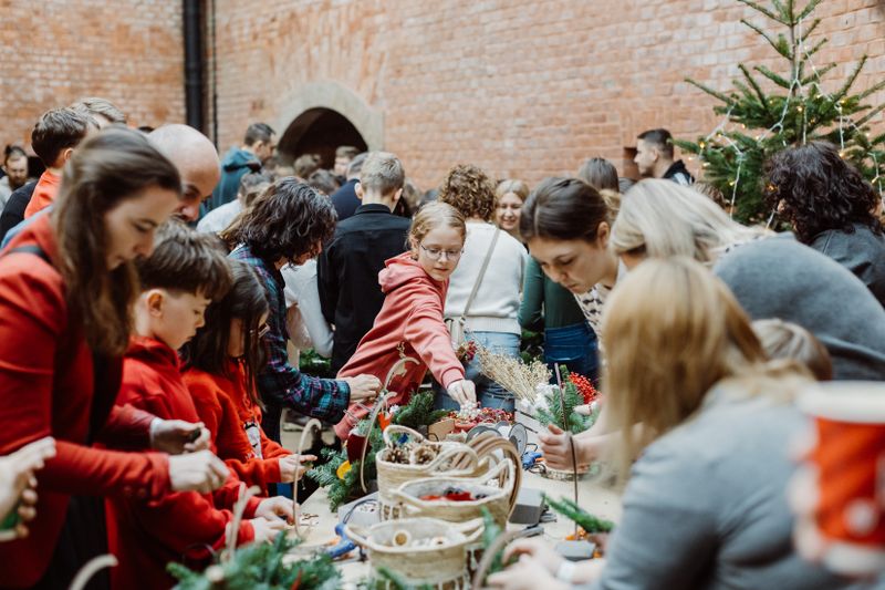 Nasi pracownicy z rodzinami podczas warsztatów mikołajkowych, wspólnie tworzący ozdoby świąteczne.
