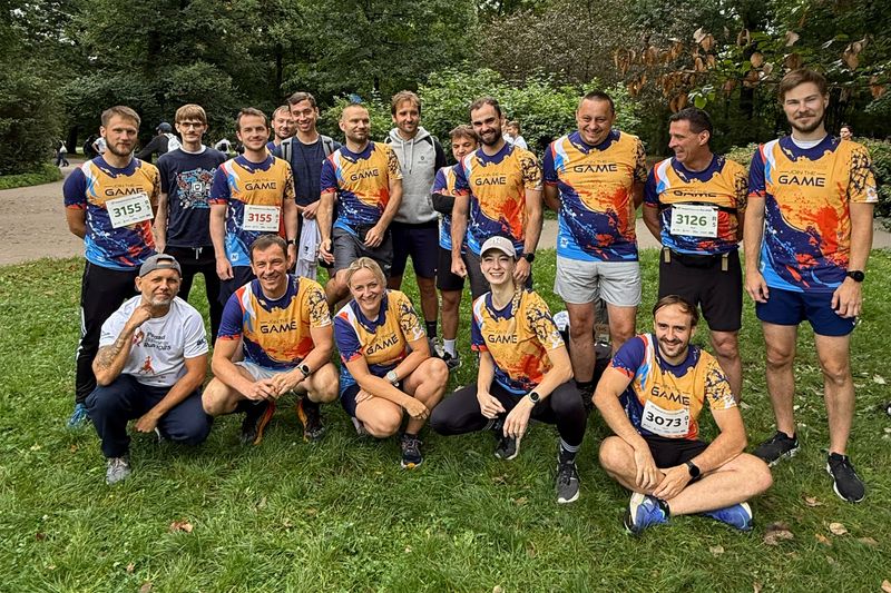 Grupa pracowników Novomatic Technologies Poland w firmowych koszulkach, pozująca wspólnie przed biegiem Poland Business Run.